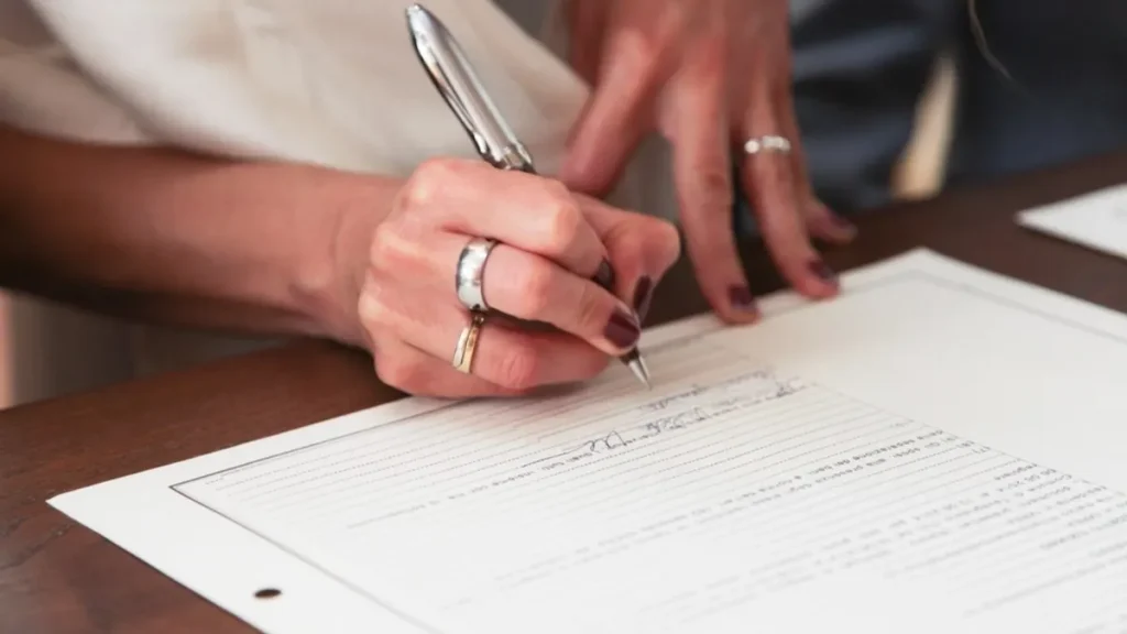 Job seeker reviewing how to write a resume on paper at a wooden desk